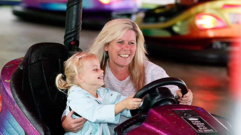 Woman and child steering pink bumper car at family fun day event