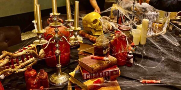 An ornate table setting with skulls, books, blood and candles put together for a Halloween house event.