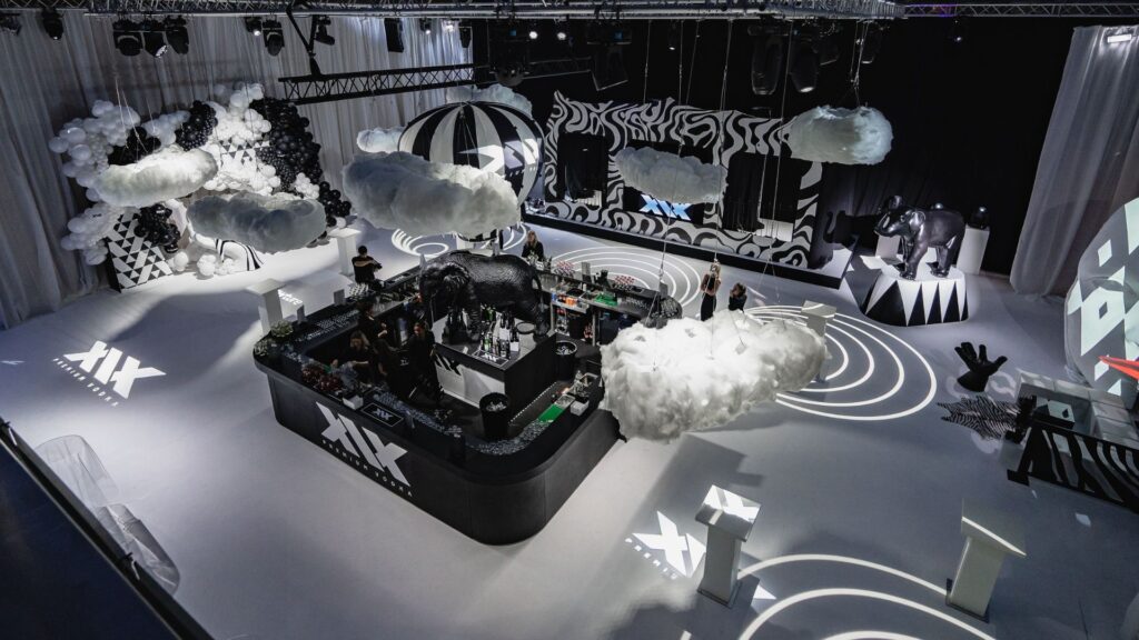 Aerial view of event space with floating balloon bar, clouds, projection lighting, props and stage.