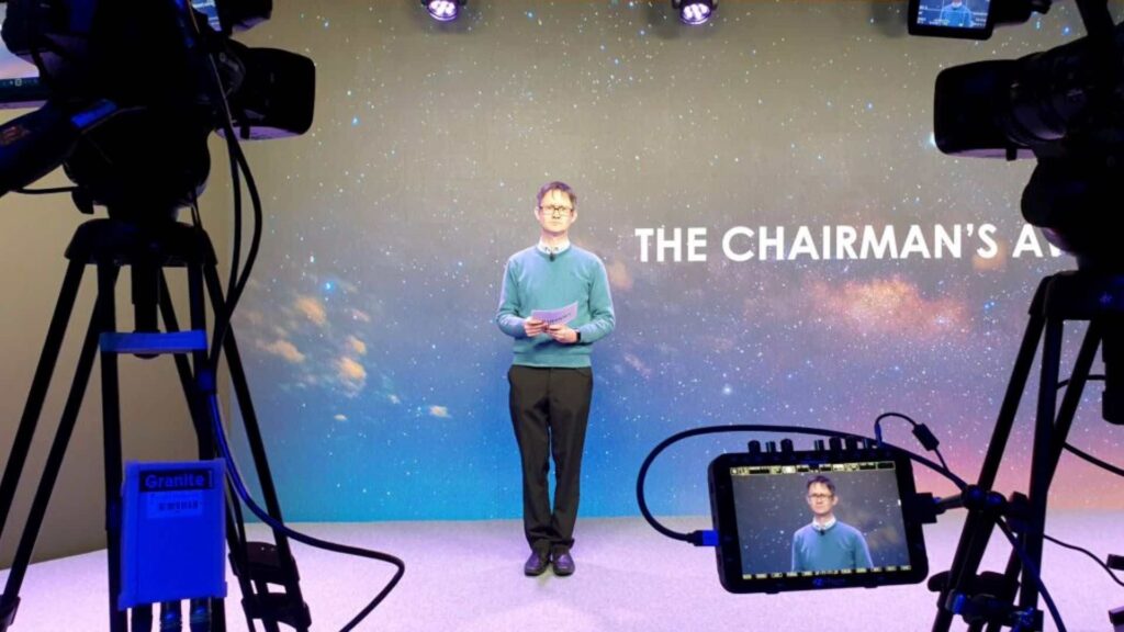 Guest speaker at conference event on stage talking to virtual audience.