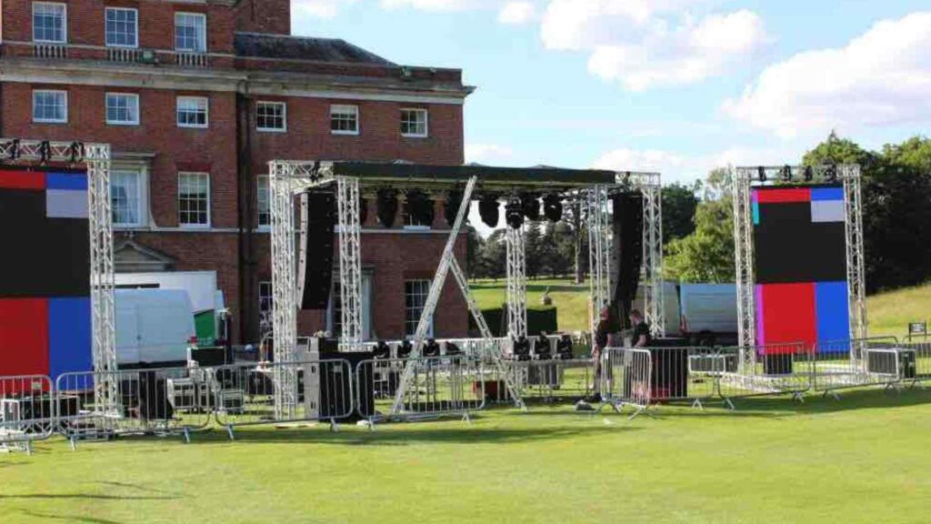 Team setting up stage, lighting and AV in outdoor event space.
