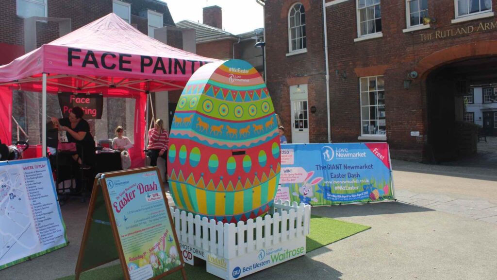 An easter community event planned by Julia Charles event management at Newmarket town centre promoting easter egg hunt for children with face painting and vibrant egg installation.