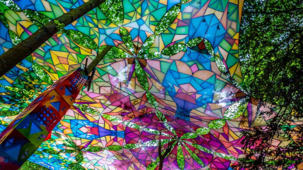 Outdoor forest festival event bright, vibrant ceiling canopy mixed in with trees.