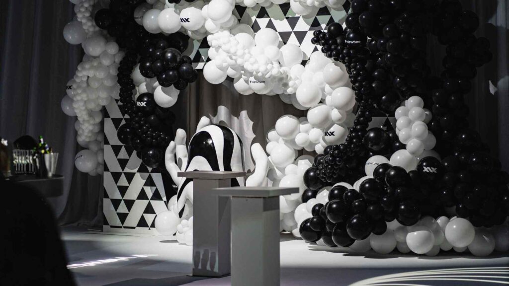 Black and white photo backdrop with black and white balloons, hand prop and white projection lighting.