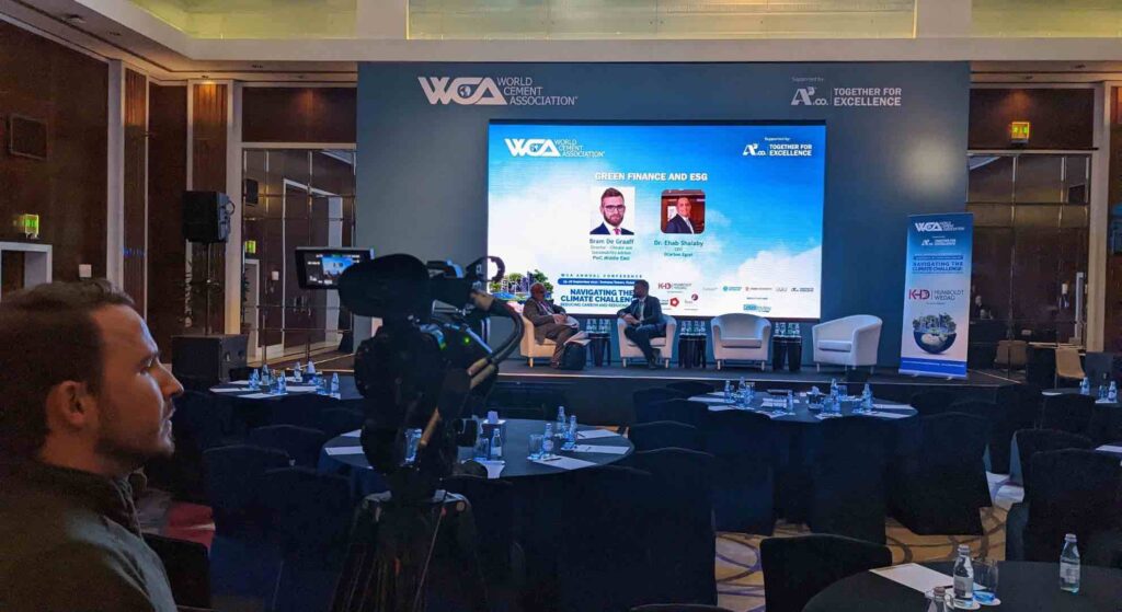 WCA conference organised by conference company with delegates sat on stage and a man filming the scene.