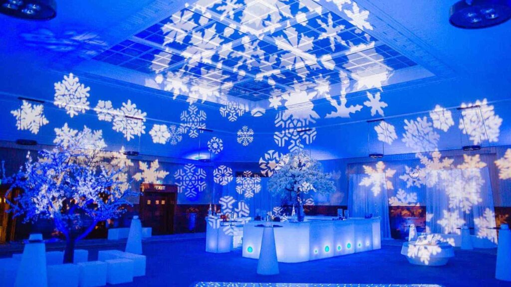 Winter Wonderland Themed Event Production with large white snowflake light projections on ceiling, walls and floor along with blue ambient lighting.