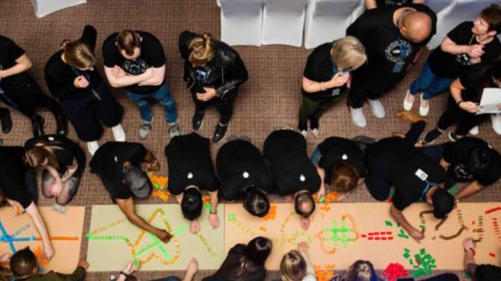 Staff taking part in dominoes team building activity at conference.