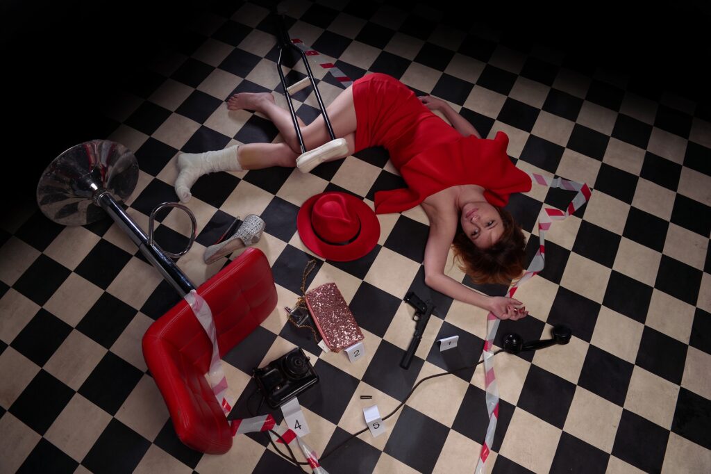 Murder Scene of a Female Character in a luxury silk red dress on a black and white checkered floor as part of our Virtual Murder Mystery Game.