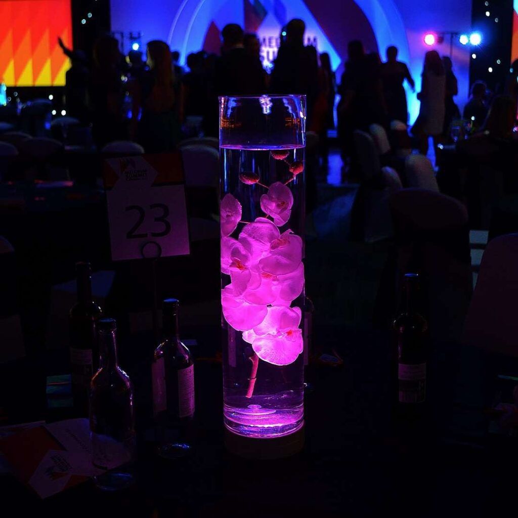 Illuminated pink floating flower table centrepiece for events.
