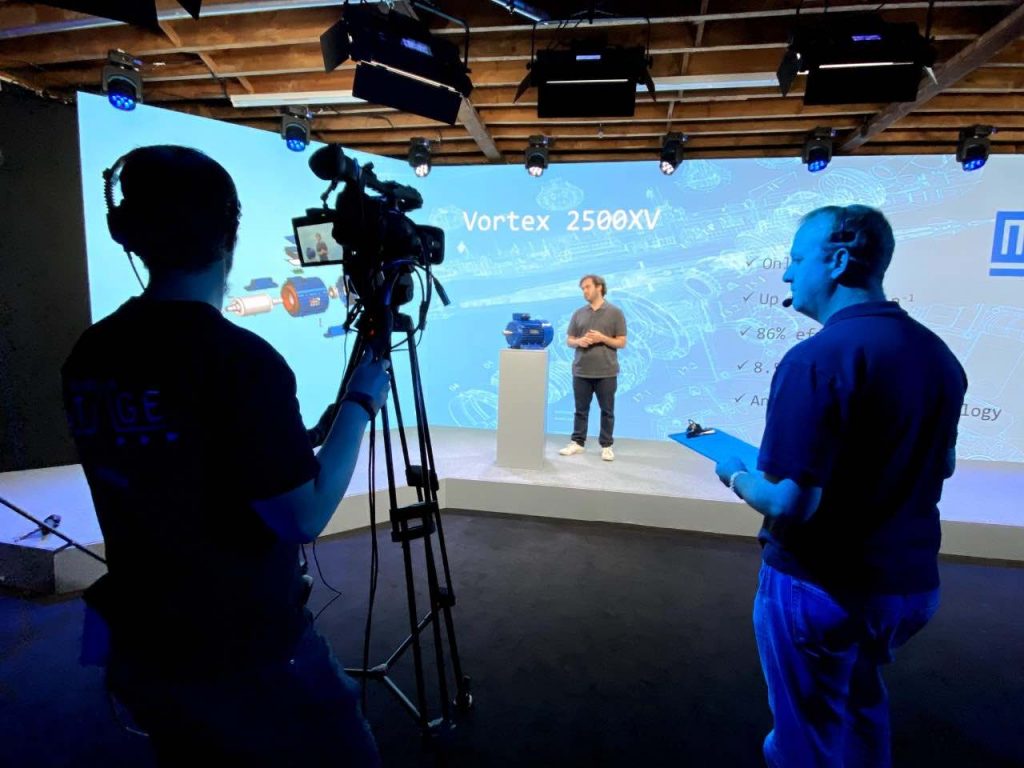 Man on stage presenting virtual confernce being captured by studio filming team provided by Event management company