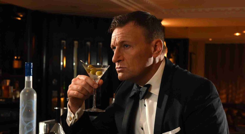 Daniel Craig lookalike in a 007 suit sipping a martini.