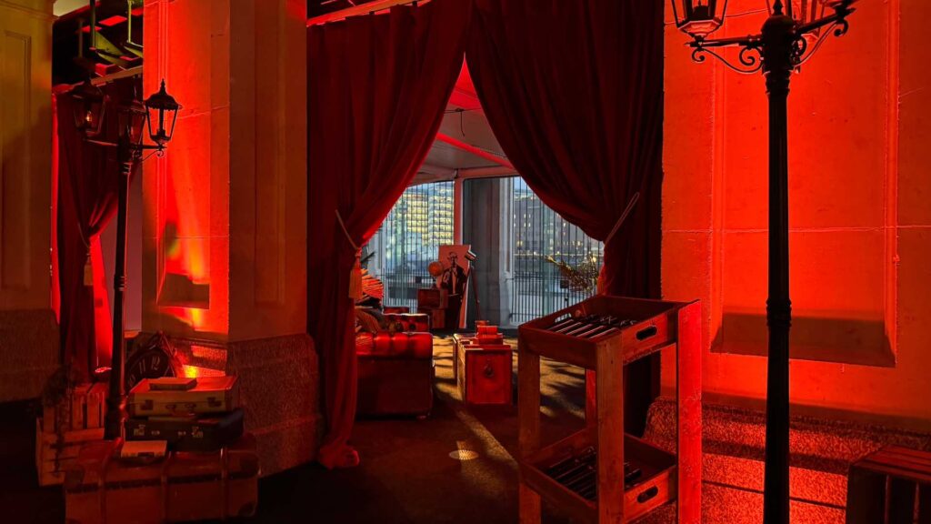 Red lighting illuminating a sophisticated bond inspired themed lounge area at a gala dinner.