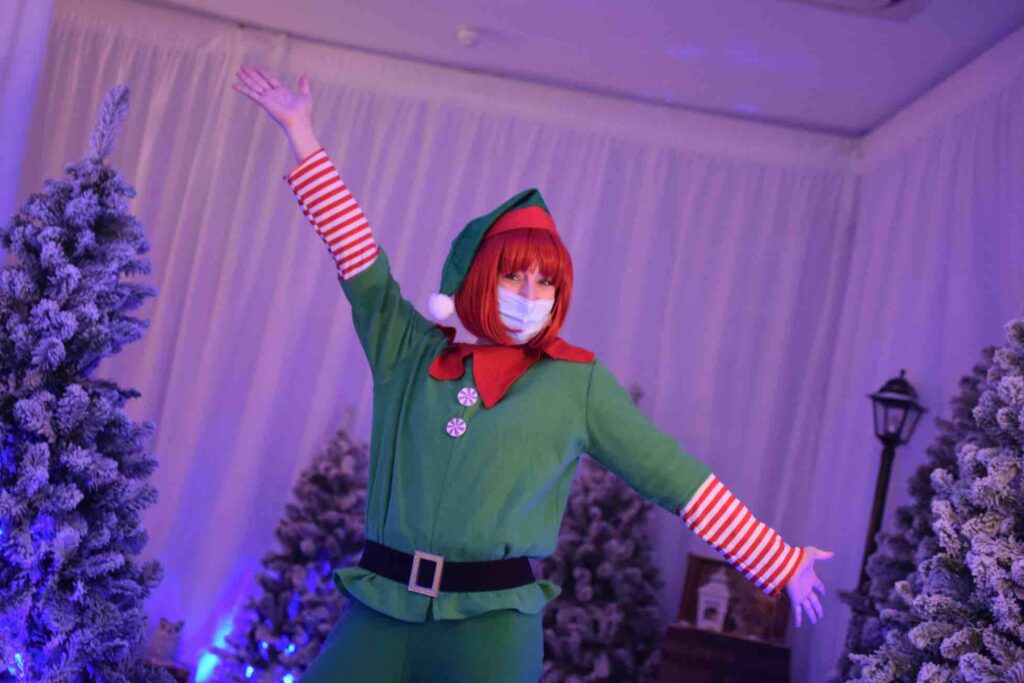 Dancing elf performer posing in winter wonderland at Christmas shopping centre activation.