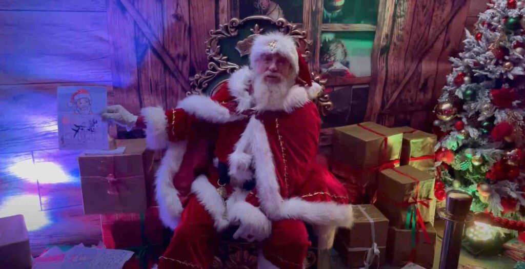 Father Christmas sat in Santas grotto showing children's drawings