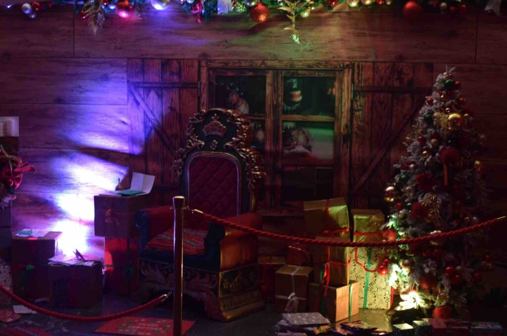 Santa's grotto, with garlands, Christmas presents and Santa's chair.