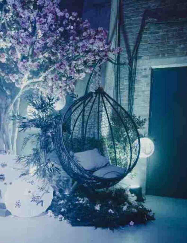 Swinging chair under cherry blossom tree decorated with Japanese inspired paper umbrellas and lantern props. Book for Tokyo themed events.