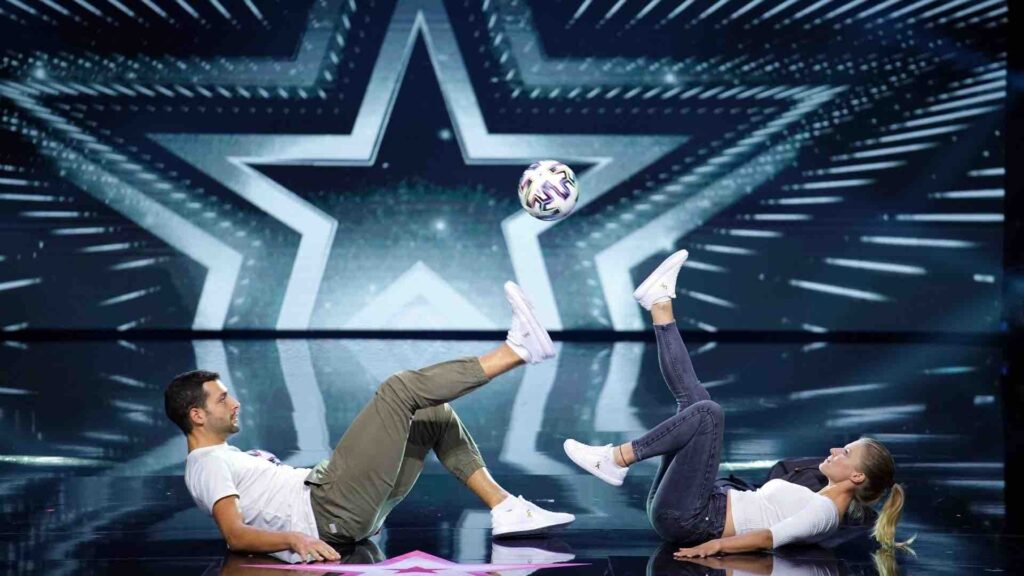 Male and female football tricksters performing football freestyle act on stage.