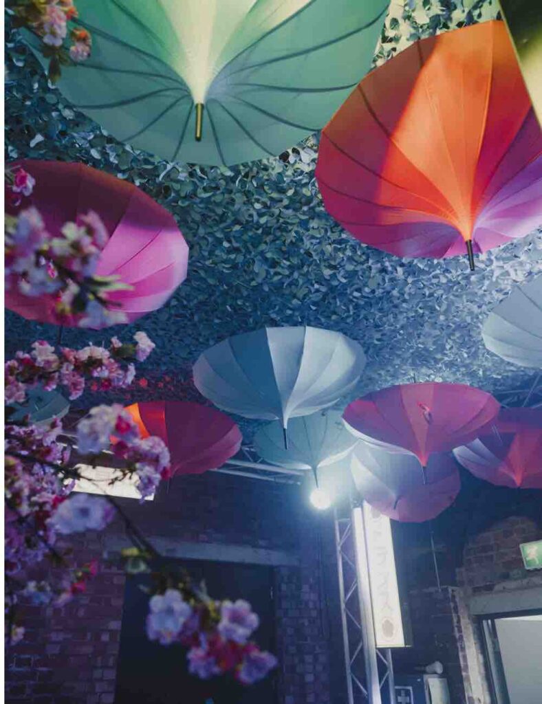 Colourful umbrellas hung from floral cover canopy at Tokyo themed event event.