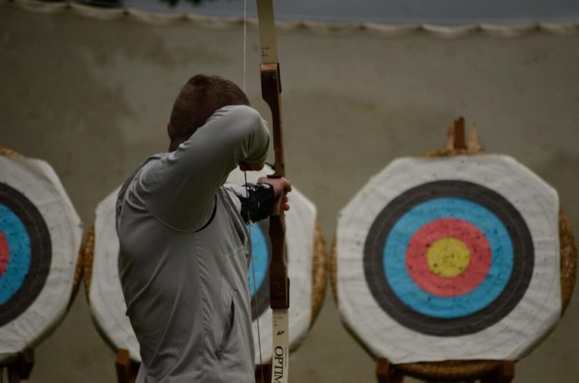 Adult taking part in our archery activity aiming his bow at a target.