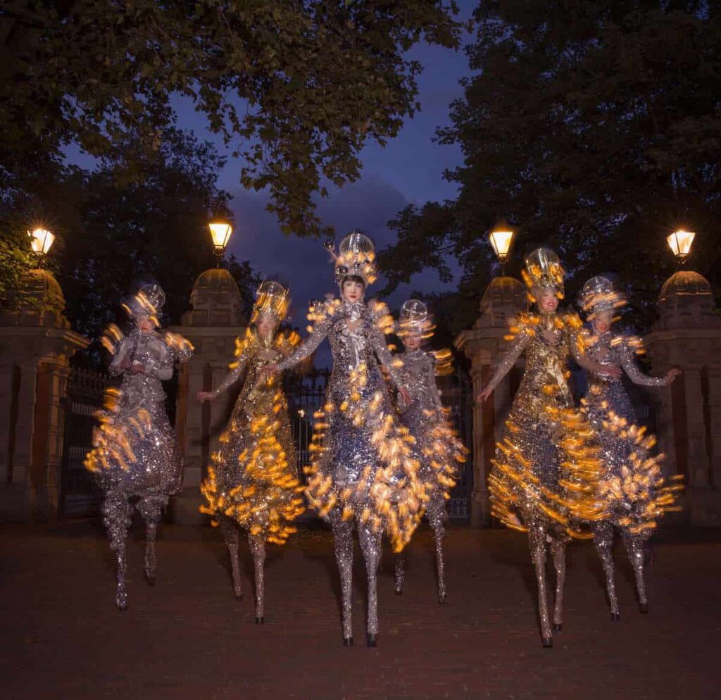 Group of stilt walkers in glitter ball costumes with LED lighting.