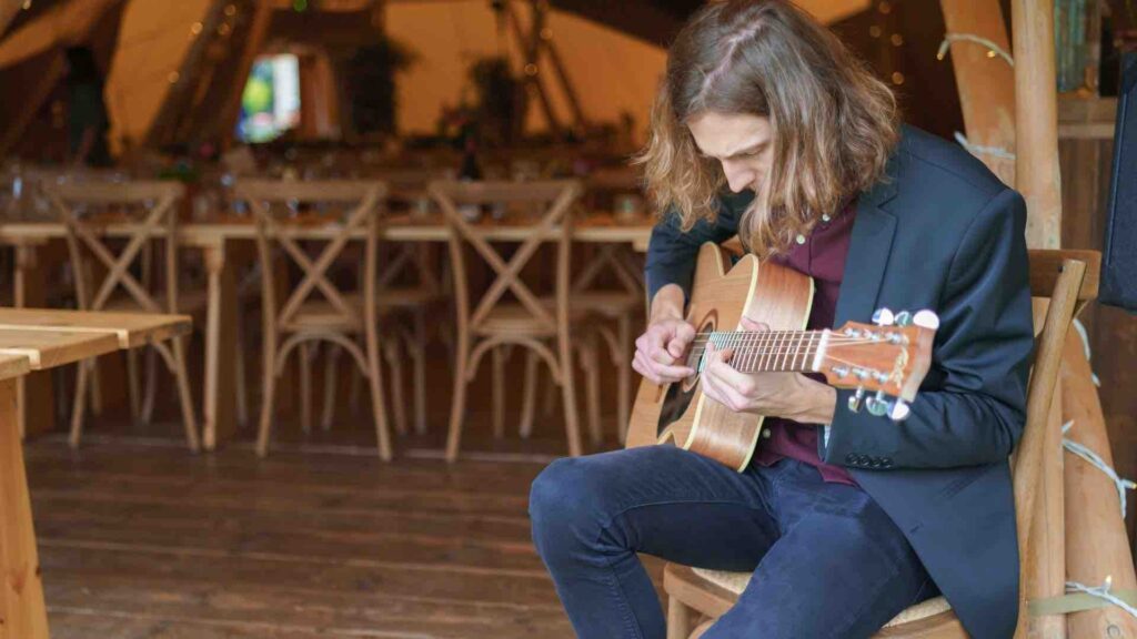 Guitarist playing songs while sitting in venue