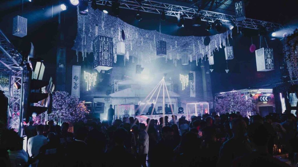Stage and crowd on dance floor with projection lighting, hanging props and rigging.