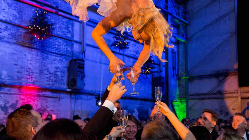Aerialist holds glass and pours champagne for guest