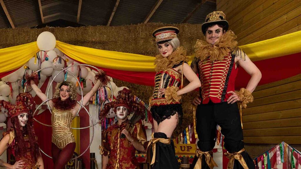 Stilt performers stand with acrobats