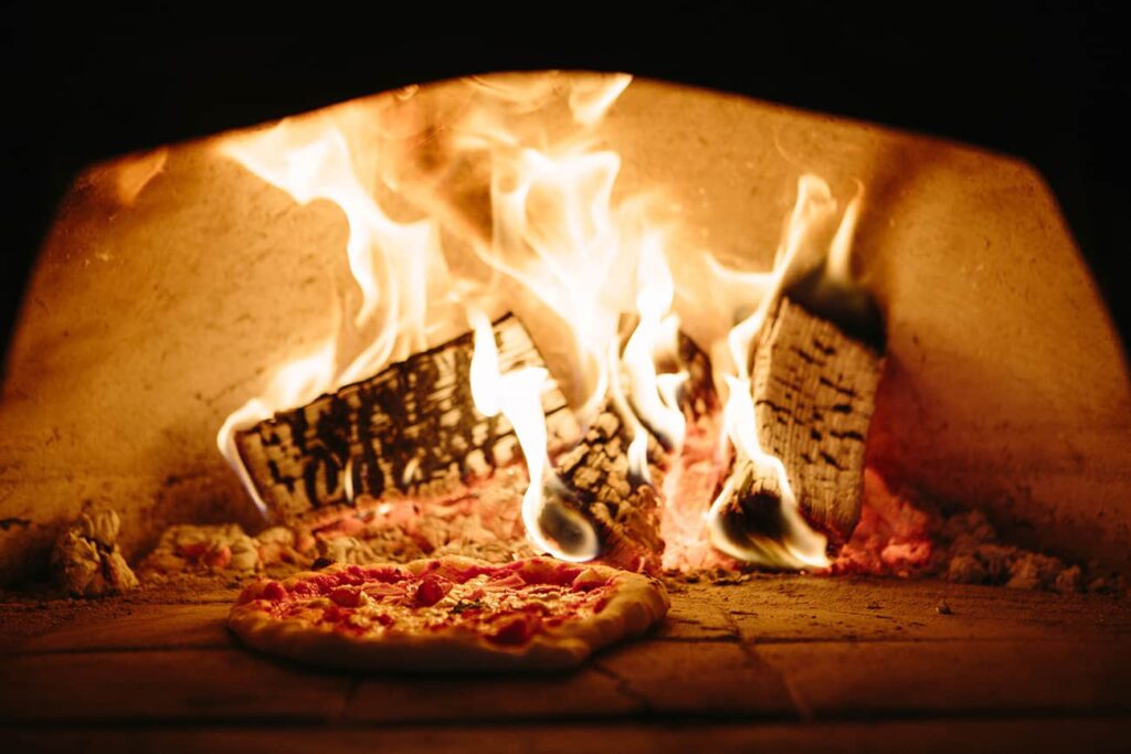 Pizza being cooked in a pizza oven, provided as catering services at an event.