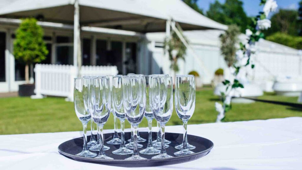 Champagne glasses lined up ready to serve to guests at all white party theme.
