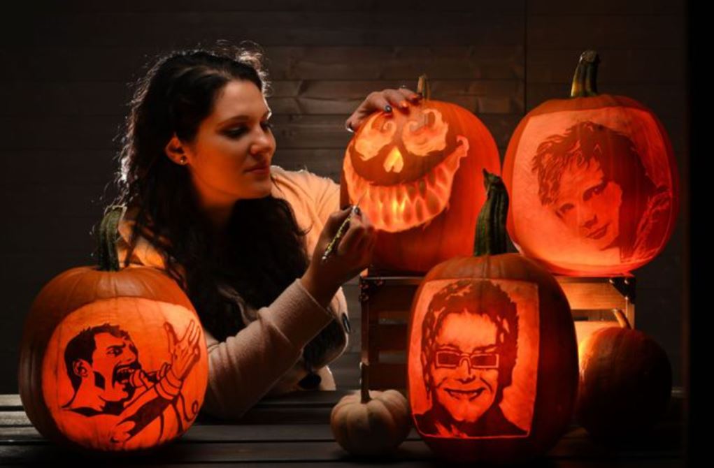 Pumpkin Carver surrounded by carved pumpkins, providing a corporate Halloween pumpkin carving workshop.