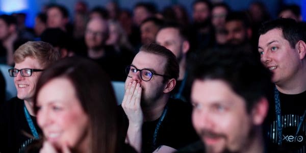Audience listening to a motivational speaker on stage at a sales kick off event in Milton Keynes, UK.