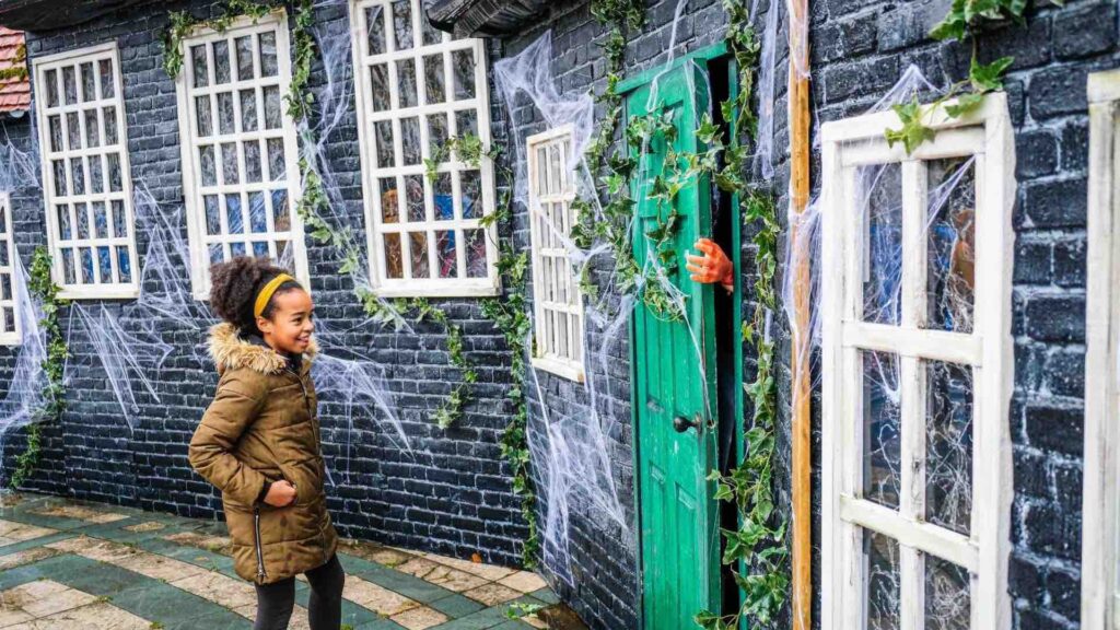 Hand poking out from behind door to wave at child at Halloween Event