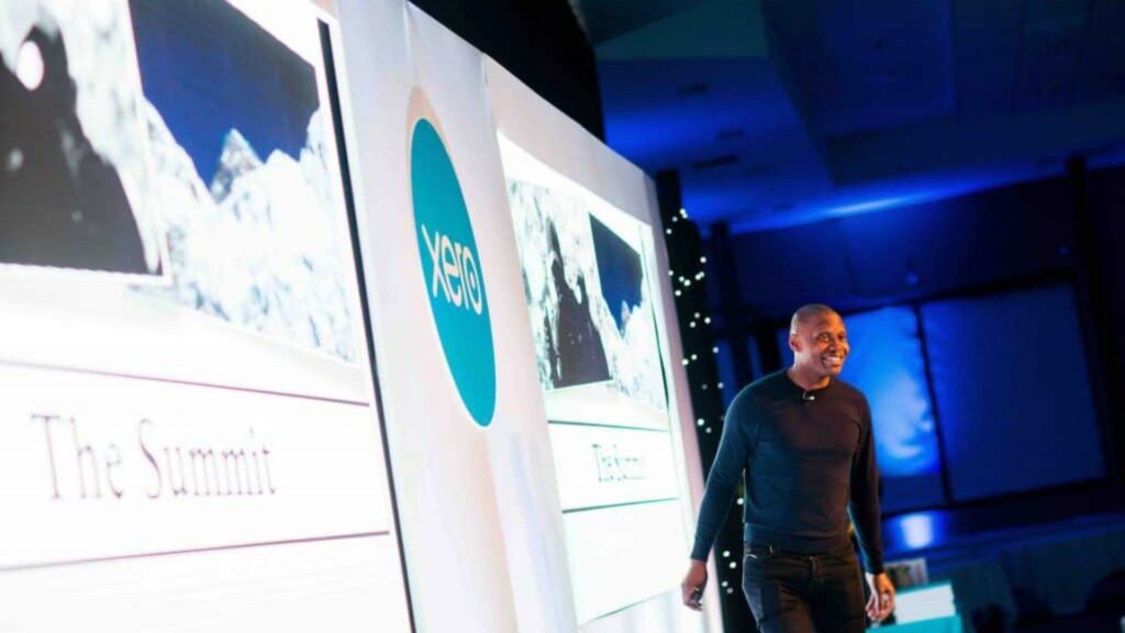 Guest speaker on stage talking to audience at conference event.