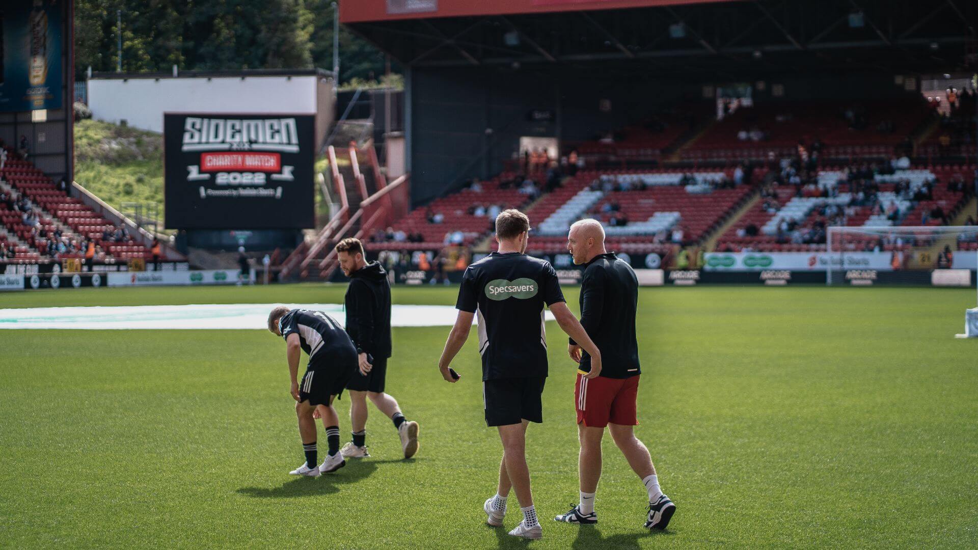 Theo Baker, Calfreezy, Behzinga and ChrisMD walking on the Charlton Stadium pitch.