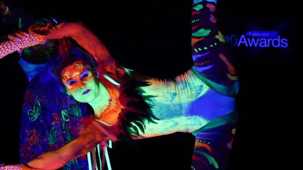 Acrobatic dancer wearing UV paint performing the splits while standing