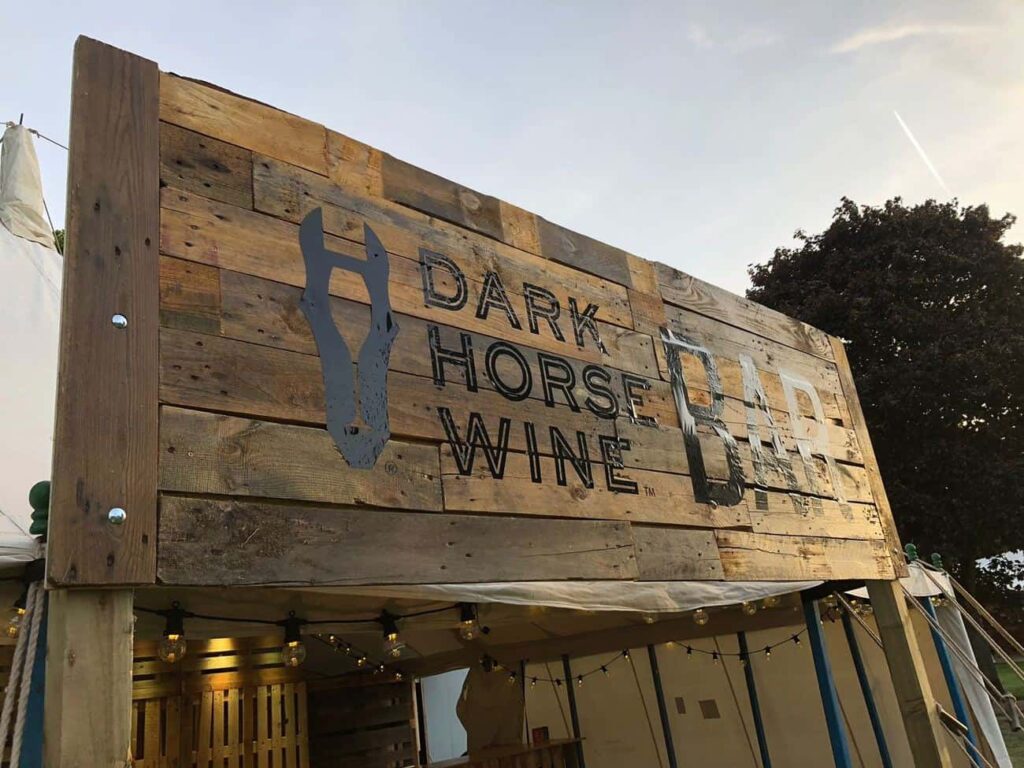 'Dark Horse Wines' brand logo on wooden sign outside marquee.
