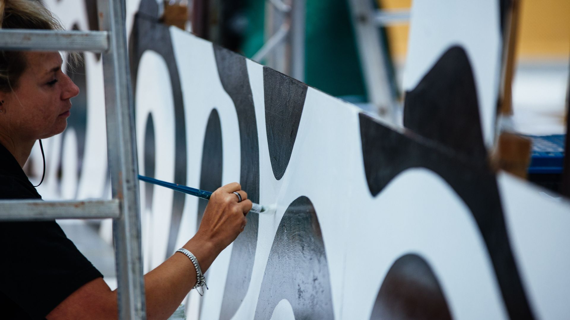 Team painting the stage paneling in black and white.