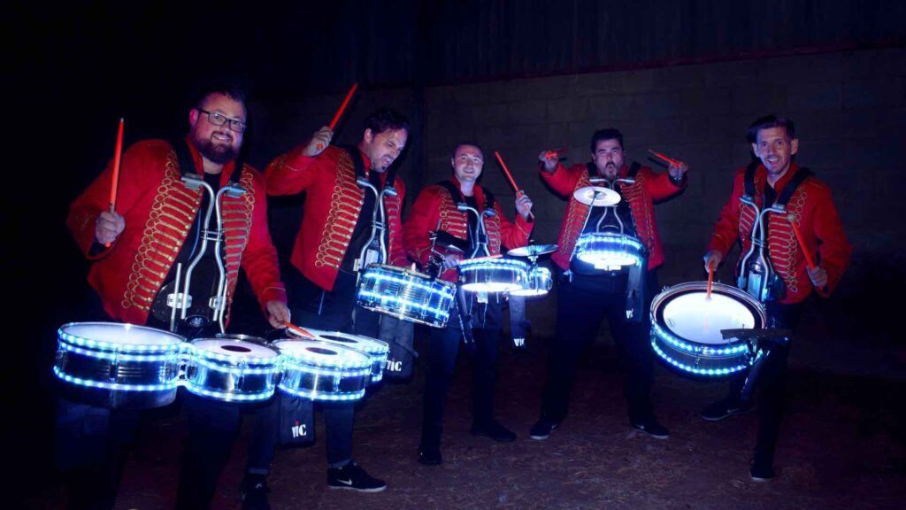 Five drumming performers holding LED drums