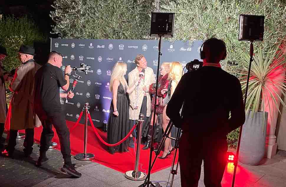 Guests being interviewed on red carpet at influencer mansion party.