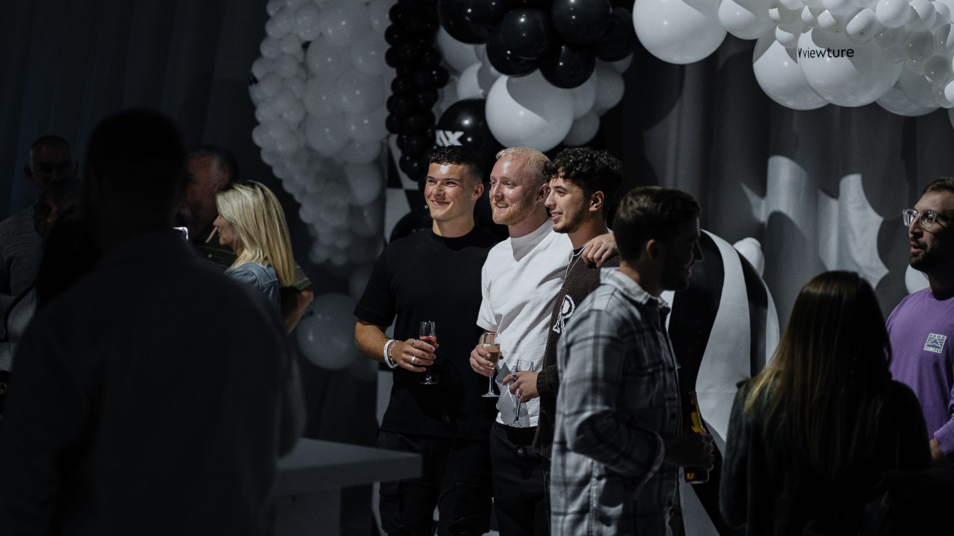 Theo Baker, TheBurntChip and guests taking photo by the branded balloon wall at the Sidemen charity match 2022 after party.