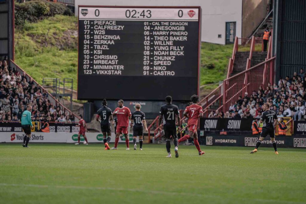 Digital scoreboard showing the named and positions of the YouTubers and Sidemen playing in charity football match.