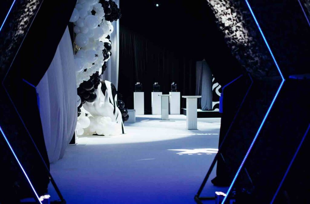 Giant black and white balloon installation, white tables and branded projections on the floor greet guests as they enter dream circus party.