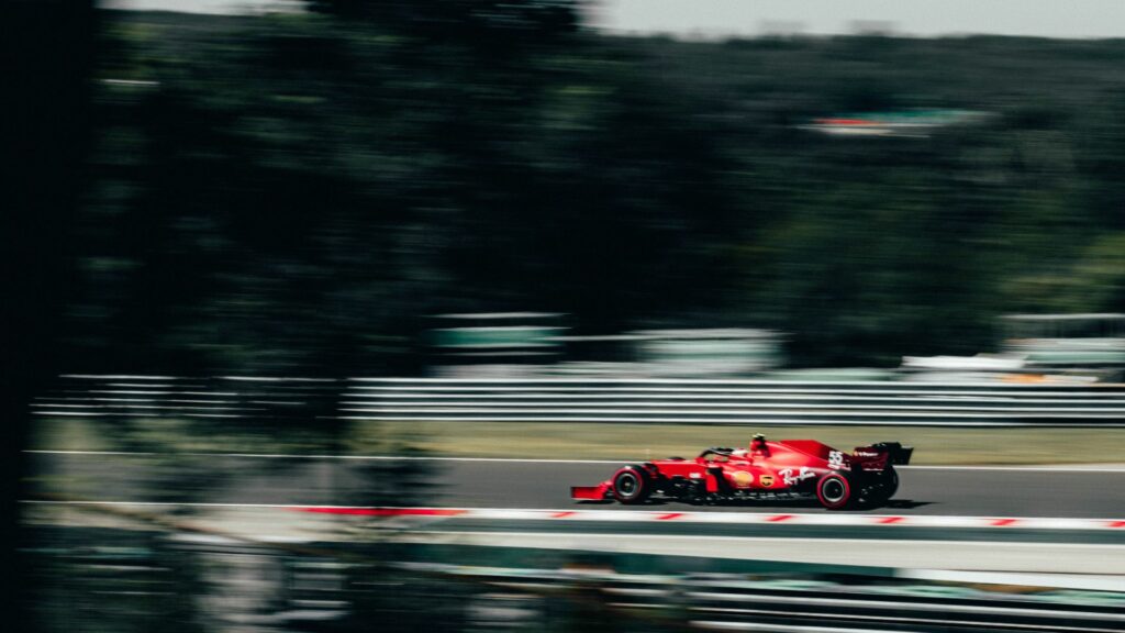 Red F1 car racing around track.
