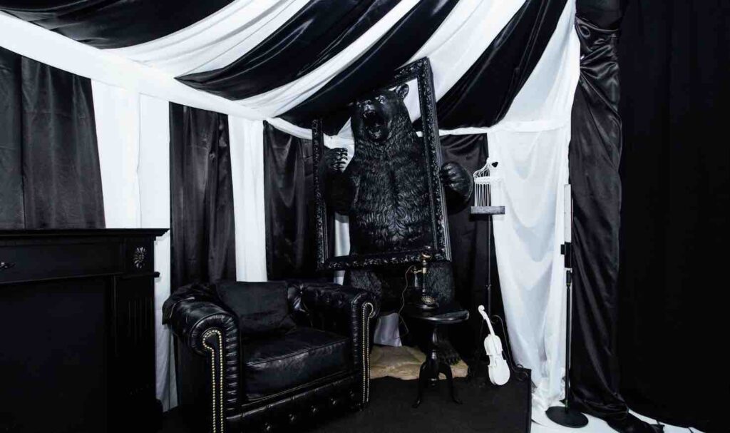 All black bear holding black frame in a black and white circus tent structure created for dream circus party.