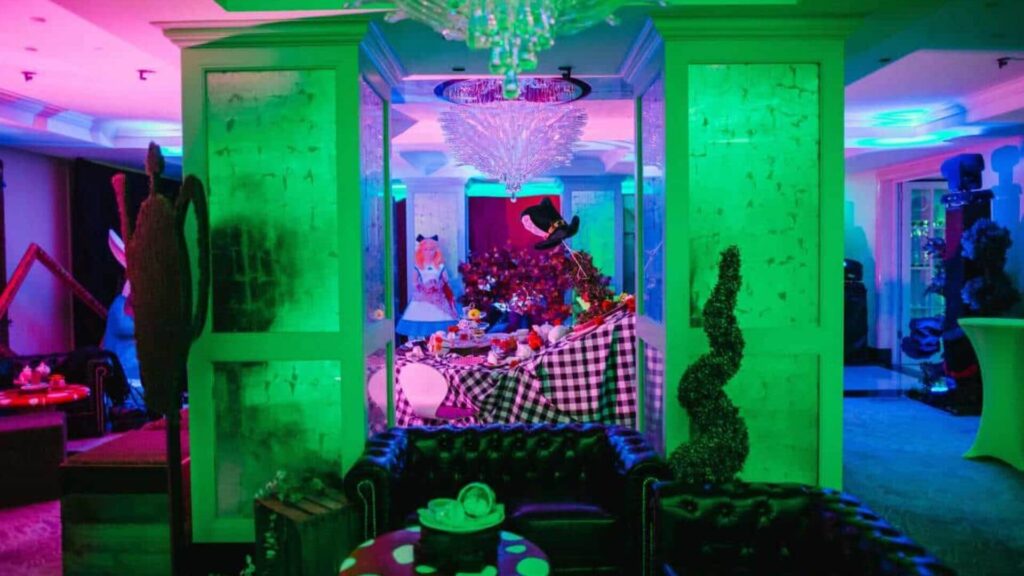 Alice In Wonderland Themed Event Production with large feature table with decorations, bespoke plant props, seating and projection lighting.
