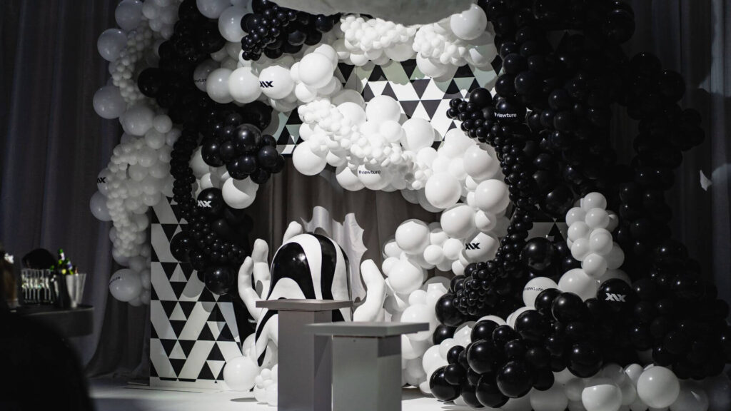 Black and White Balloon Wall with branding and large hand prop.