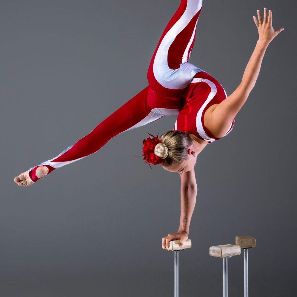 Circus entertainer wearing red and white leotard and balancing on poles