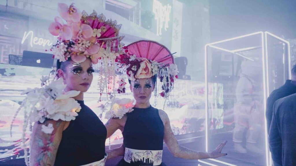 Oriental themed walkabout act with pink and flower headdress and black costume.