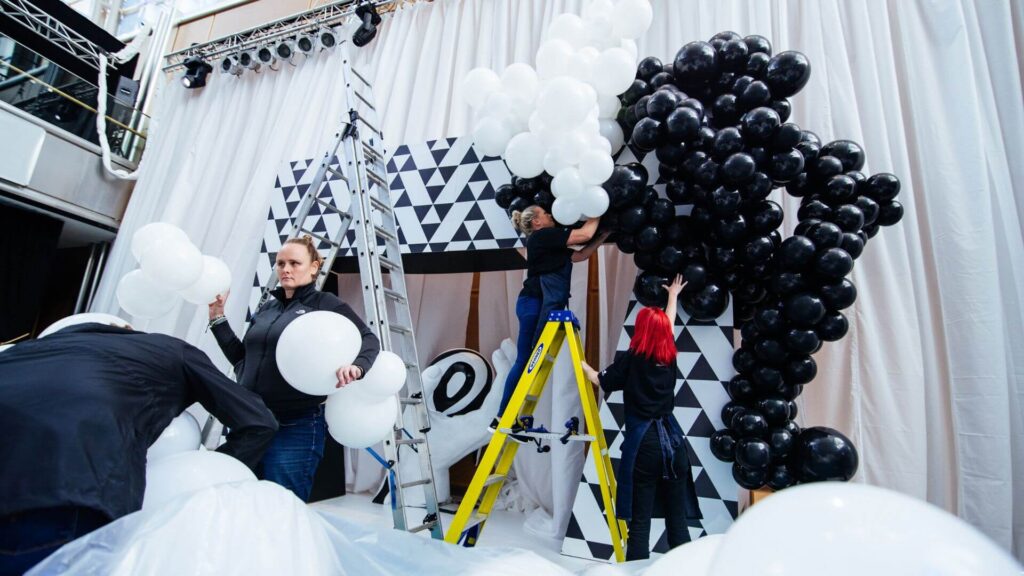 Team setting up balloon feature wall in event space.